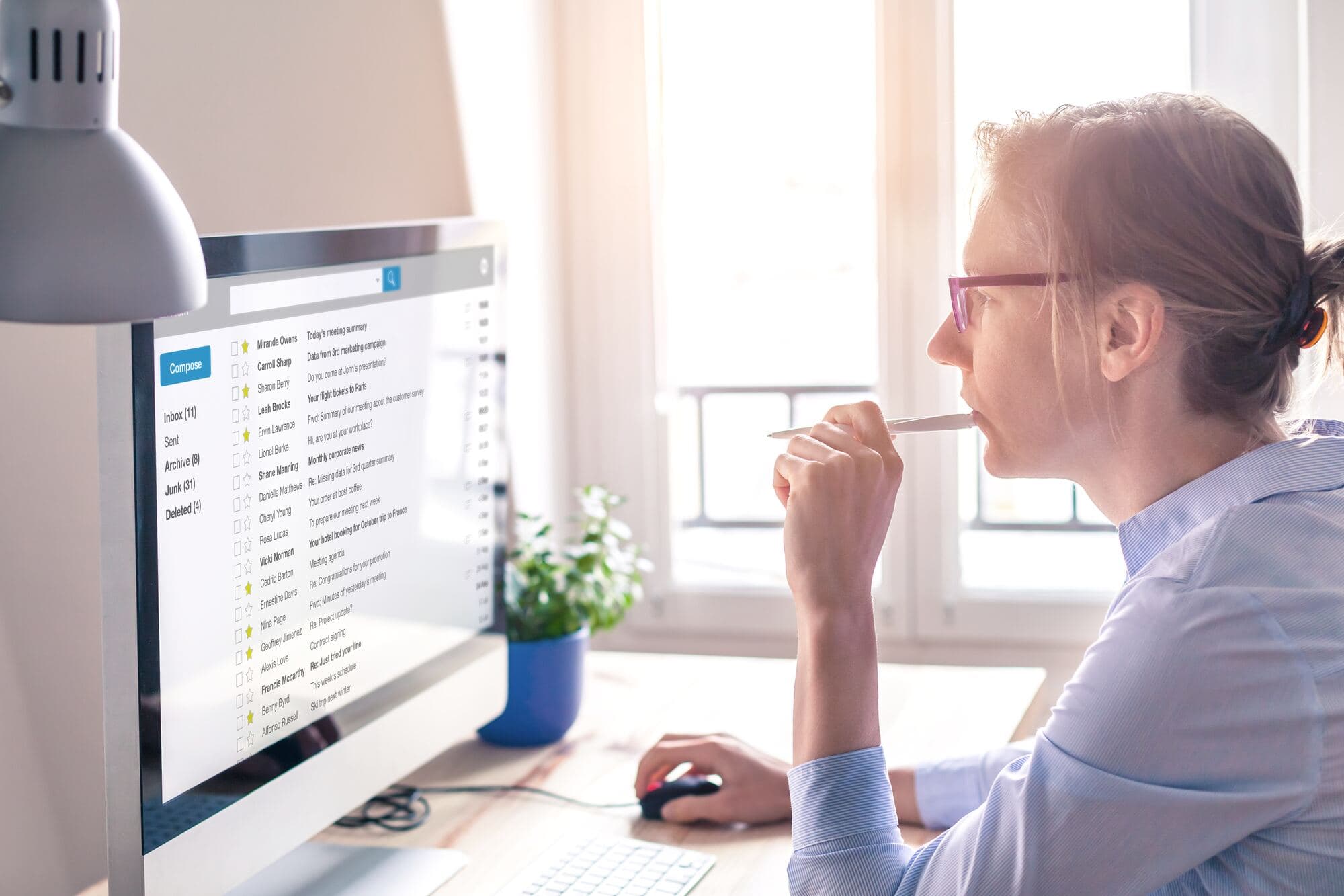Kobieta przy biurku patrzy na skrzynkę pocztową na monitorze
