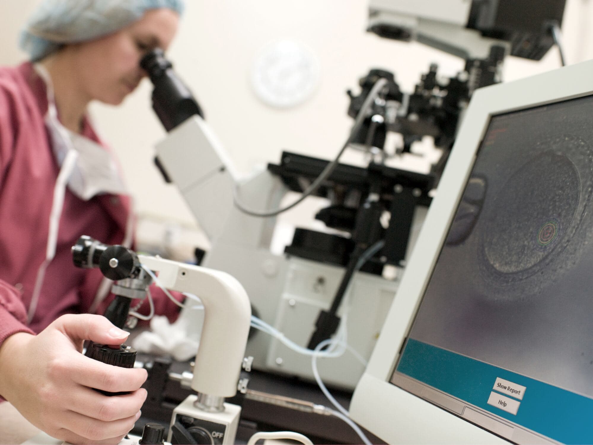Embriolożka pracuje przy mikroskopie z monitorem w laboratorium