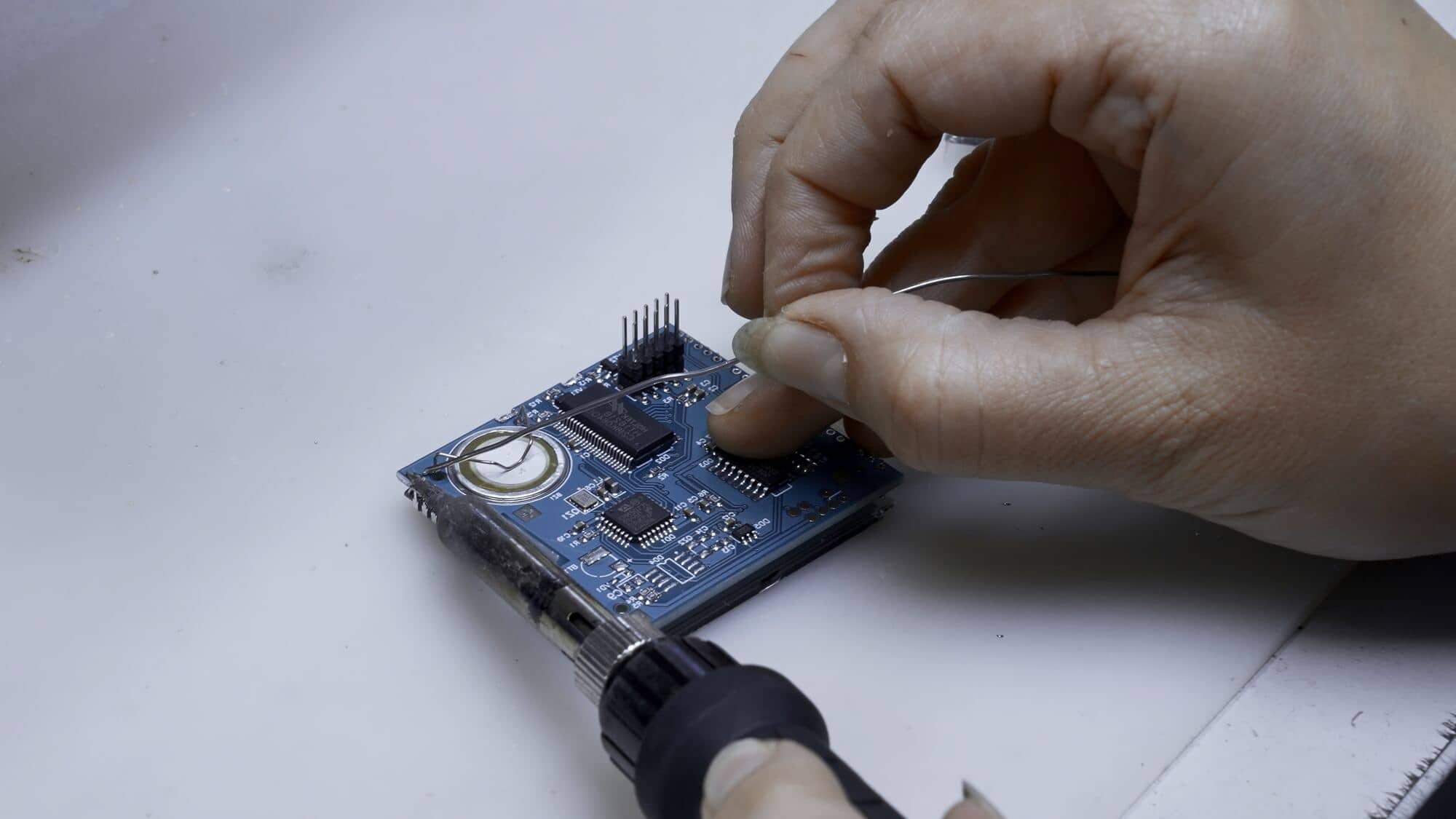 Dłoń lutuje płytkę elektroniczną