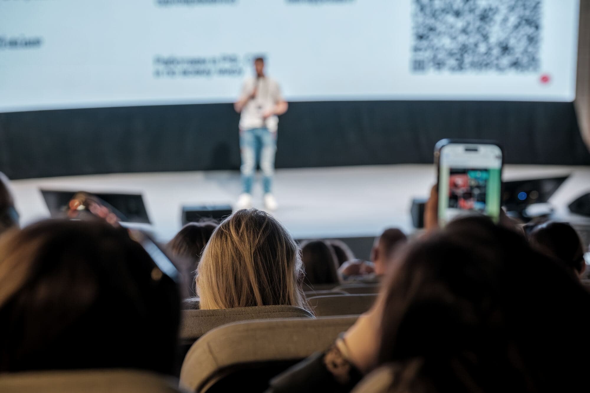 Prelegent na scenie, widzowie nagrywają telefonami