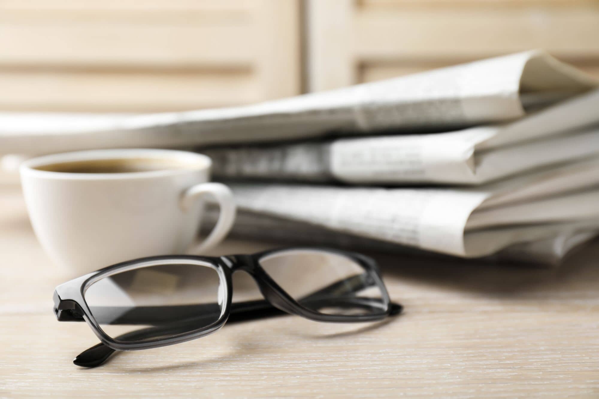 Gazety, filiżanka kawy i okulary na stole